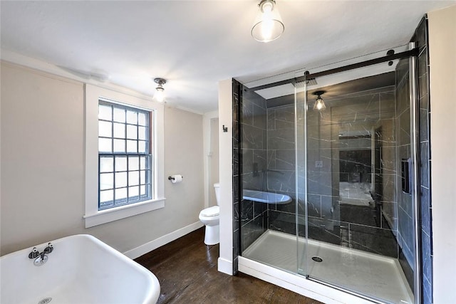 full bathroom featuring wood finished floors, baseboards, a stall shower, a freestanding bath, and toilet