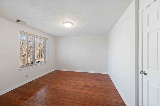 unfurnished room featuring hardwood / wood-style flooring, baseboards, visible vents, and a textured ceiling