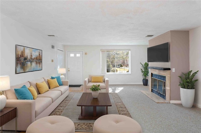 carpeted living room featuring a textured ceiling, a premium fireplace, visible vents, and baseboards