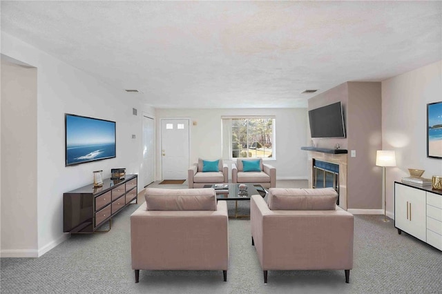 living area with baseboards, a glass covered fireplace, visible vents, and light colored carpet