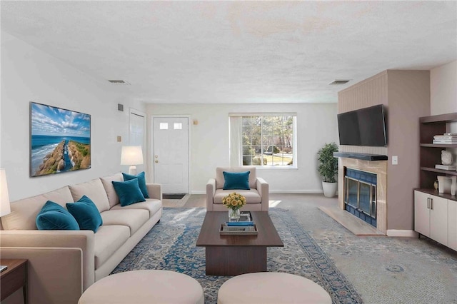 living area featuring a textured ceiling, a fireplace, visible vents, and baseboards