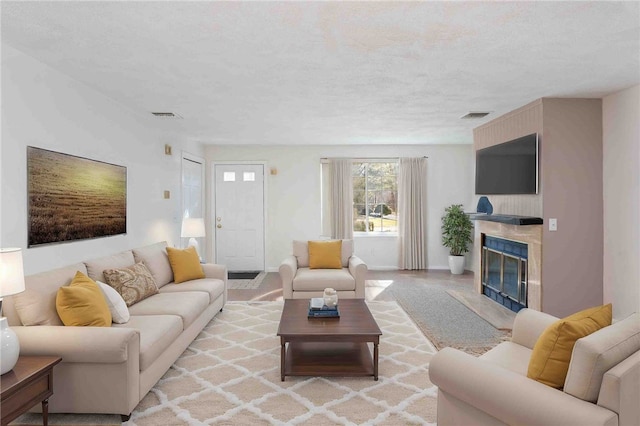 living room with a textured ceiling, a premium fireplace, visible vents, and baseboards