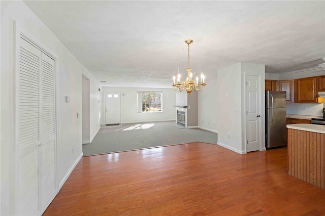 interior space featuring brown cabinetry, light countertops, wood finished floors, and freestanding refrigerator