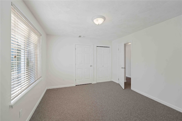 unfurnished bedroom featuring visible vents, a closet, baseboards, and carpet flooring