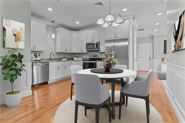 kitchen with visible vents, stainless steel appliances, crown molding, light wood-type flooring, and a sink