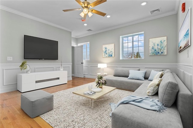 living area with light wood-type flooring, ceiling fan, visible vents, and crown molding