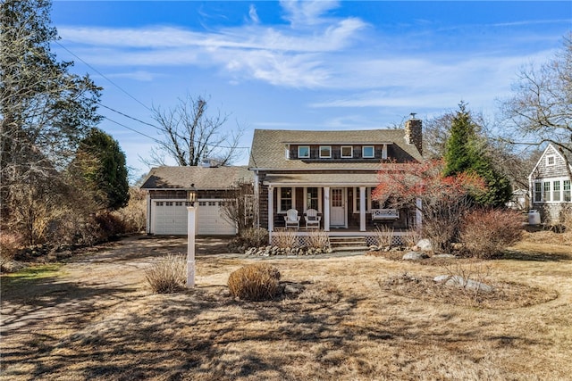 view of front facade featuring covered porch, a chimney, and an attached garage