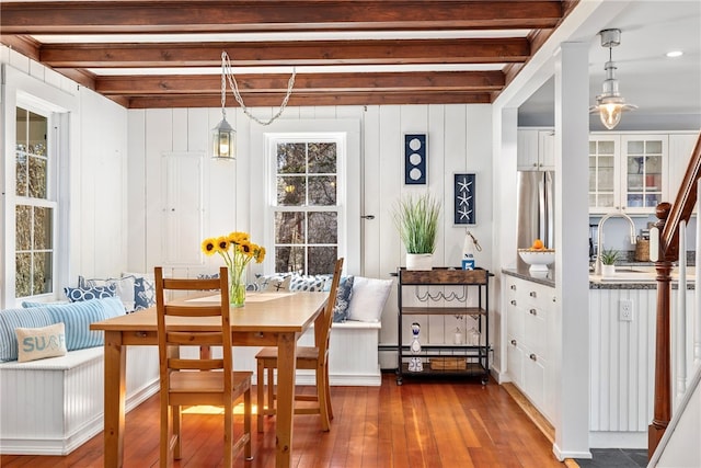 dining space with beamed ceiling, baseboard heating, and hardwood / wood-style flooring