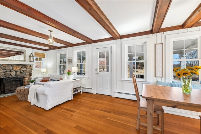 living room with baseboard heating, beamed ceiling, a fireplace, and wood finished floors