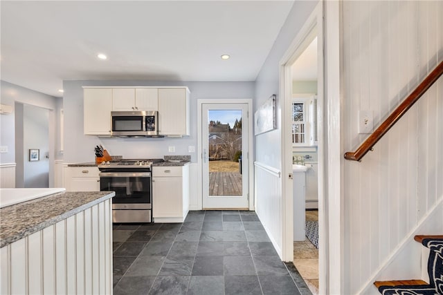 kitchen featuring a baseboard radiator, recessed lighting, appliances with stainless steel finishes, stone finish floor, and white cabinetry