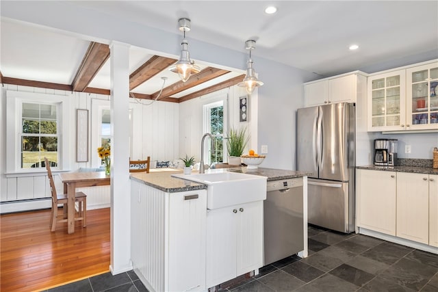 kitchen featuring glass insert cabinets, appliances with stainless steel finishes, beamed ceiling, decorative light fixtures, and a sink