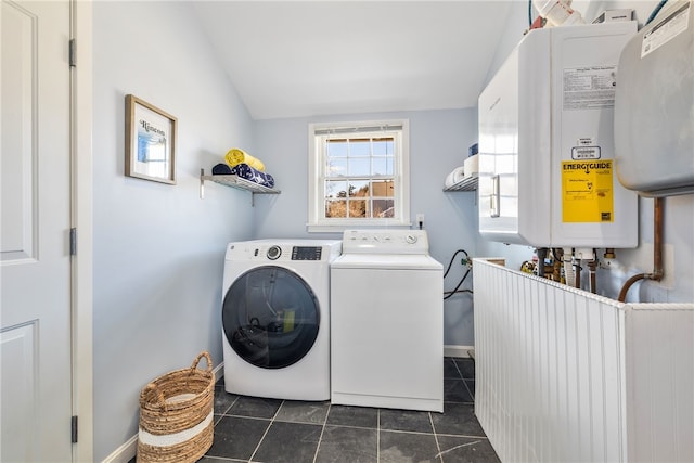 washroom with tankless water heater, laundry area, dark tile patterned flooring, baseboards, and washing machine and clothes dryer