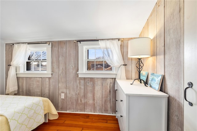 bedroom featuring wood walls, wood-type flooring, and multiple windows