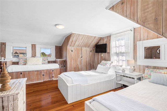 bedroom with lofted ceiling, hardwood / wood-style flooring, and wooden walls