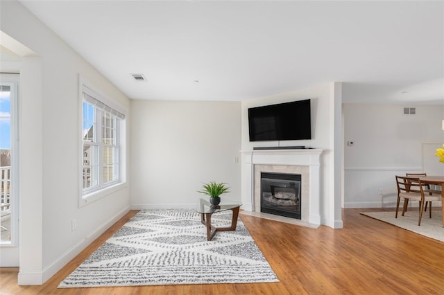 living area featuring light wood finished floors, a tile fireplace, and visible vents