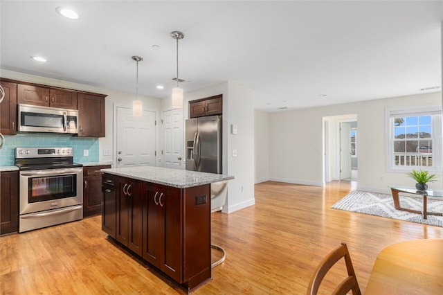 kitchen featuring stainless steel appliances, light wood-style floors, decorative backsplash, and dark brown cabinets