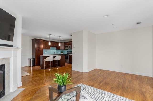 living area with visible vents, baseboards, light wood-style flooring, a fireplace, and recessed lighting