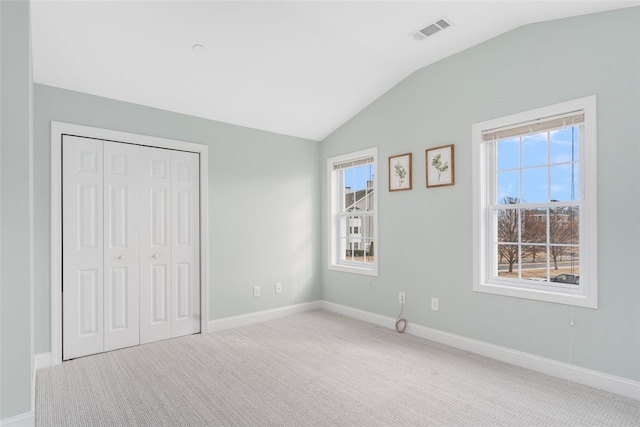 unfurnished bedroom featuring baseboards, visible vents, lofted ceiling, carpet, and a closet