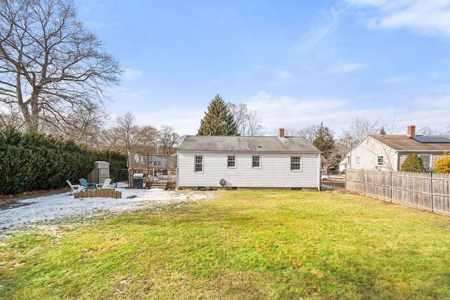 rear view of house featuring an outdoor fire pit, a lawn, a chimney, fence, and a deck