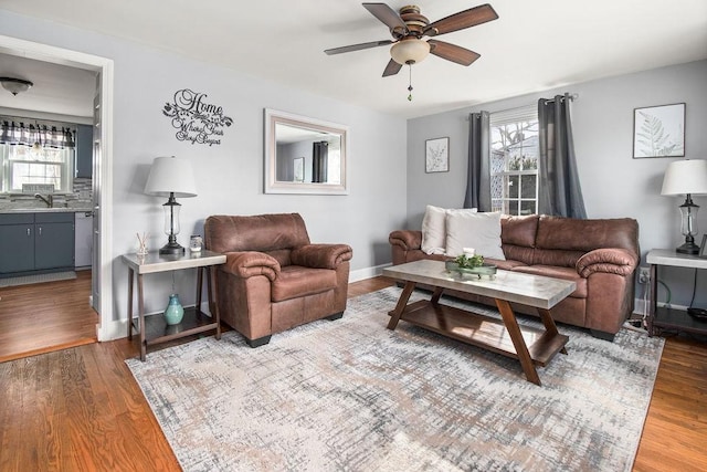 living room with a ceiling fan, baseboards, and wood finished floors