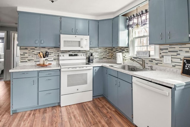 kitchen with white appliances, dark wood finished floors, blue cabinets, light countertops, and a sink