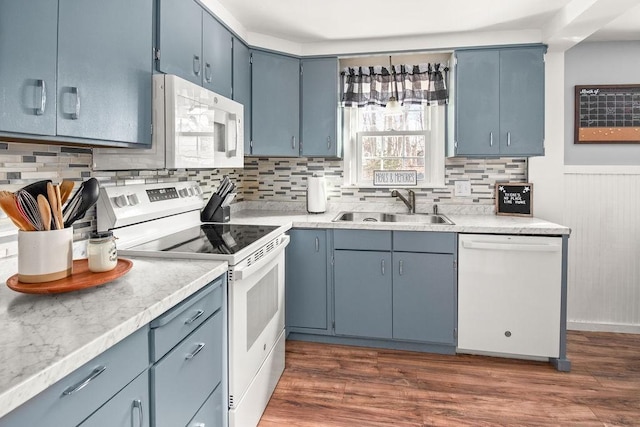 kitchen featuring white appliances, dark wood-style floors, blue cabinets, light countertops, and a sink