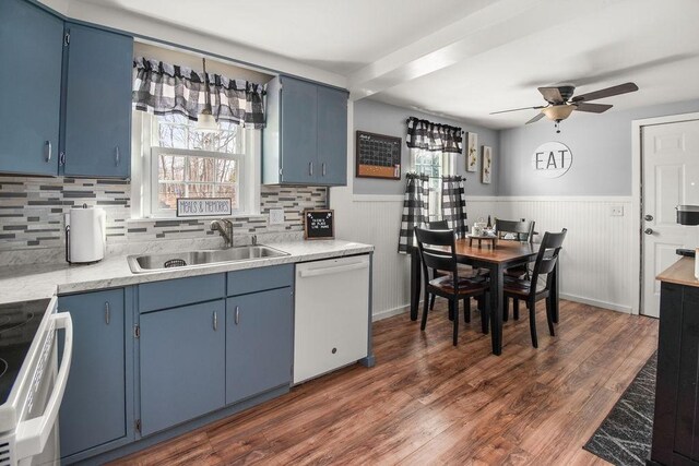 kitchen featuring blue cabinets, white appliances, a sink, and wainscoting