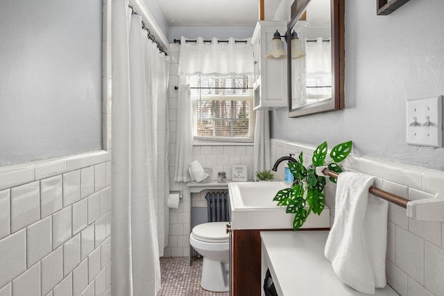 bathroom with a wainscoted wall, tile walls, toilet, radiator heating unit, and vanity