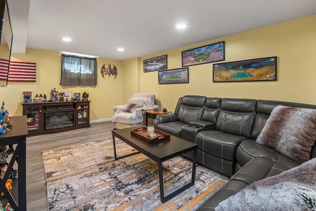 living area with baseboards, a glass covered fireplace, wood finished floors, and recessed lighting