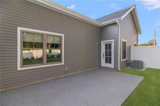 rear view of house with a patio area, central AC, fence, and a lawn