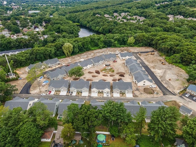 drone / aerial view featuring a forest view, a water view, and a residential view