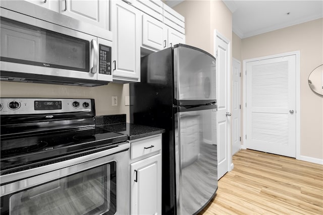 kitchen featuring light wood finished floors, dark countertops, appliances with stainless steel finishes, ornamental molding, and white cabinetry