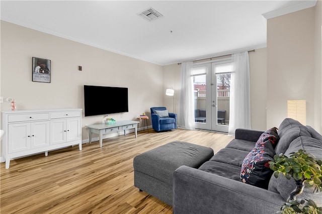 living area with light wood finished floors, french doors, ornamental molding, and visible vents