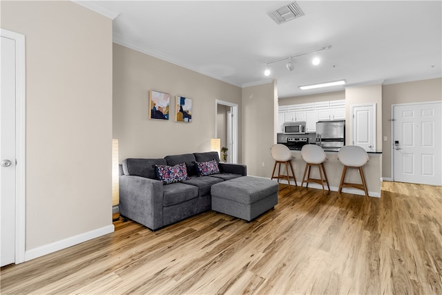 living area with light wood-style flooring, visible vents, baseboards, and ornamental molding