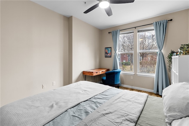 bedroom with a ceiling fan, baseboards, and wood finished floors