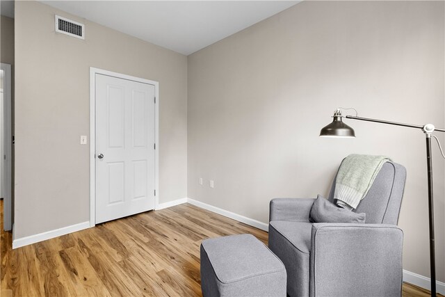 sitting room with baseboards, visible vents, and light wood finished floors