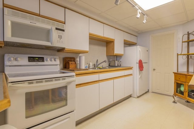 kitchen featuring white appliances, white cabinets, a sink, and rail lighting