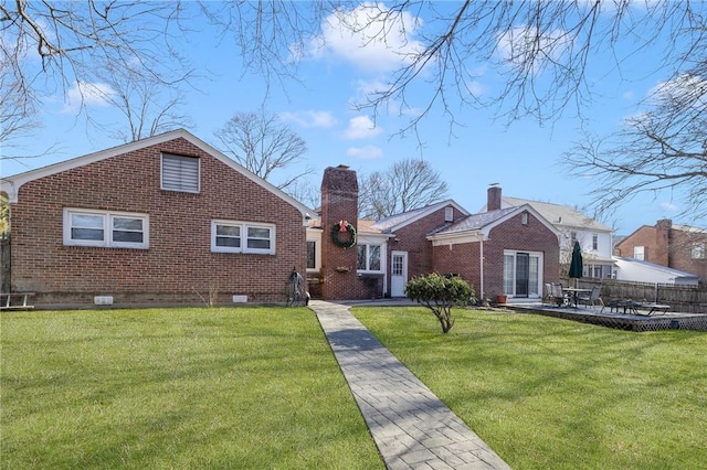 back of property with brick siding, a chimney, a lawn, a patio area, and fence