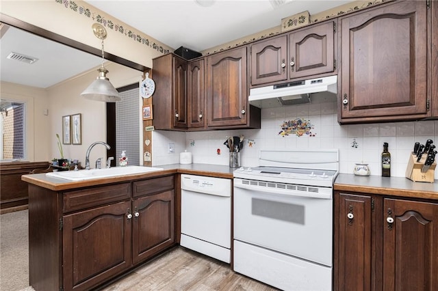 kitchen featuring white appliances, a peninsula, a sink, under cabinet range hood, and backsplash