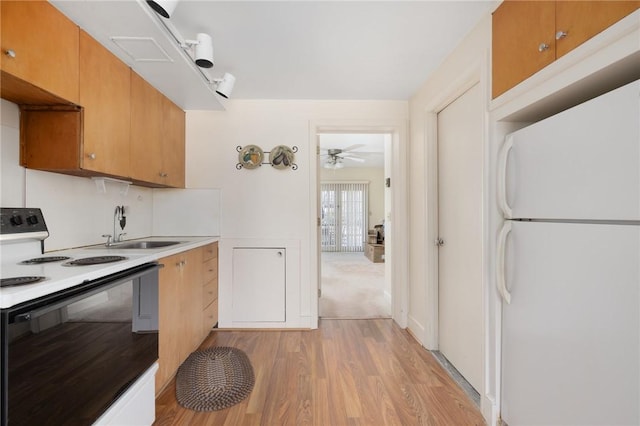 kitchen featuring ceiling fan, light wood-style flooring, white appliances, a sink, and light countertops