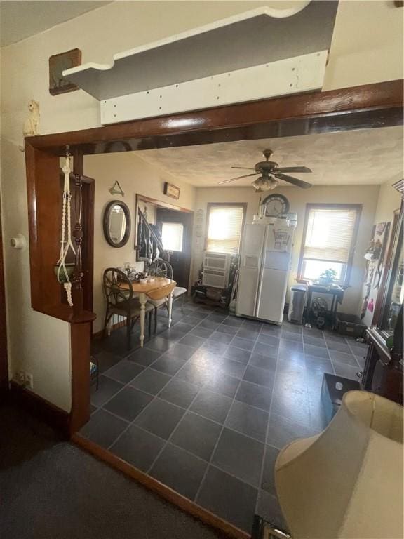 entrance foyer with ceiling fan and dark tile patterned floors