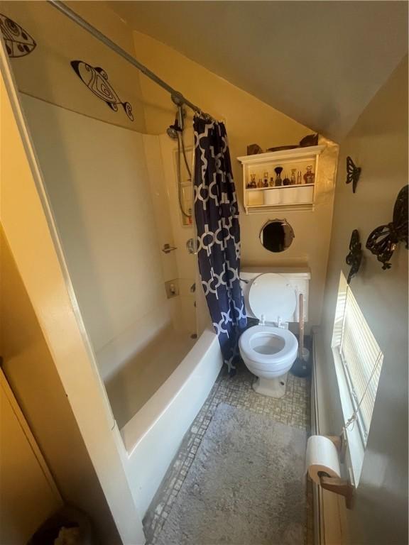 bathroom featuring vaulted ceiling, toilet, and shower / bathtub combination with curtain