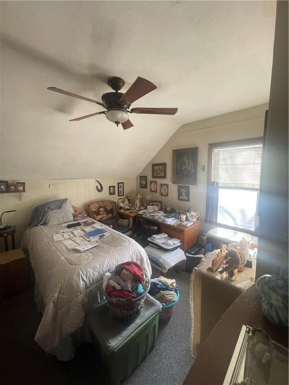 carpeted bedroom with a ceiling fan and vaulted ceiling