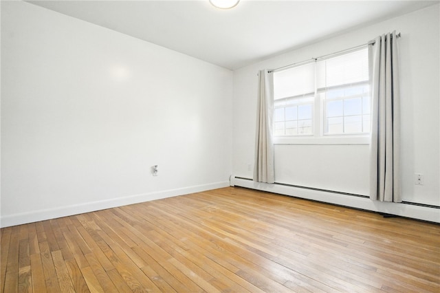 spare room with baseboards, a baseboard radiator, and light wood-style floors