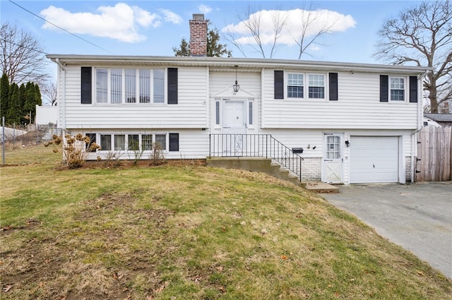 split foyer home featuring a chimney, an attached garage, fence, driveway, and a front lawn