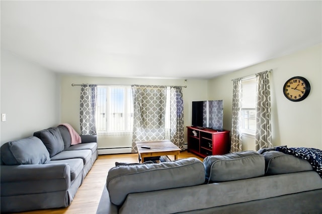 living area featuring a baseboard radiator, a healthy amount of sunlight, and light wood finished floors