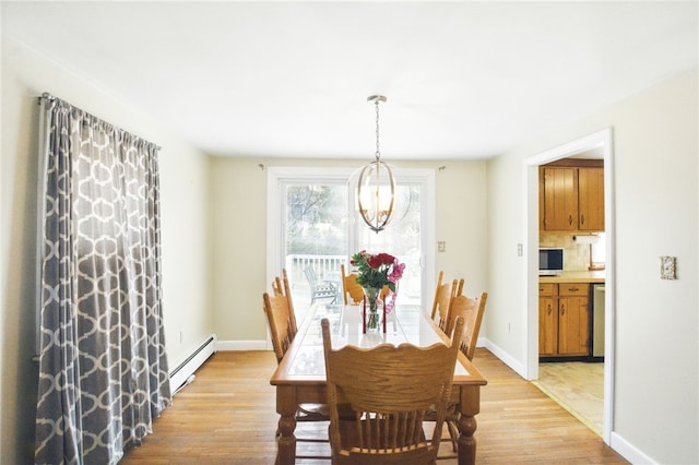 dining area with a baseboard heating unit, baseboards, a notable chandelier, and light wood finished floors