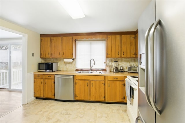 kitchen with light countertops, appliances with stainless steel finishes, a sink, and tasteful backsplash