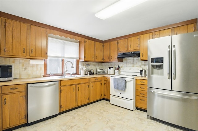 kitchen featuring under cabinet range hood, a sink, light countertops, appliances with stainless steel finishes, and brown cabinetry