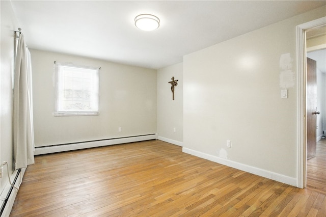 unfurnished room with a baseboard heating unit, light wood finished floors, and baseboards